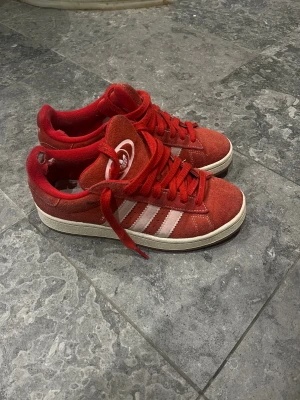 Röda Adidas campus sneakers - Säljer ett par röda Adidas campus sneakers i mocka. Slitningar innanför skon men inget som känns när man har på sig den