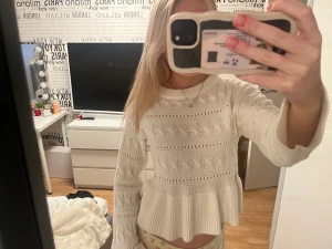 Vit stickad tröja med volang - Supersöt vit stickad tröja med volang nedtill och snyggt kabelstickat mönster. Tröjan har långärmade ärmar och rund halsringning. Ifrån Gina tricot och i nytt skick 🥰