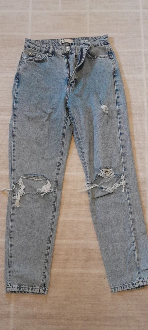 Perfekt Jeans ljusblå ripped jeans - Ljusblå jeans från Gina tricot, Perfekt Jeans i klassisk straight modell med hög midja. Snygga slitningar och stora ripped detaljer på båda benen ger ett trendigt och avslappnat uttryck. Tillverkade i robust denim med dragkedja och knapp framtill.    Skriv för frågor eller fler bilder!💕   !Endast swish!!