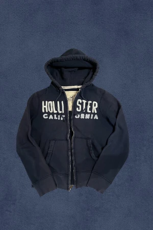 Hollister Hoodie - Sjuukt snygg och trendig hoodie från Hollister. Hoodien är i ett bra skick, lite urtvättad. Slitningarna är en del av designen. Modellen är 176, 59kg. Mått finns på bilderna. Skriv vid frågor