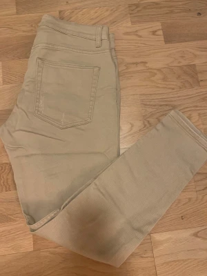 Beige skinny jeans från Vailent Pure - Snygga beige jeans från Vailent Pure i storlek M. Modellen är skinny med hög midja och har slitna detaljer på båda benen för en cool look. Klassisk femficksdesign och tillverkade i mjukt bomullsmaterial med lite stretch för extra komfort.98% bomull,2%elastan 