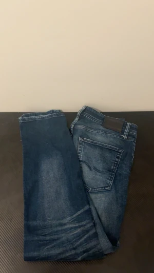 Blå jeans från Jack & Jones - Snygga blå jeans från Jack & Jones med slitningar och tvättade detaljer. Klassisk femficksmodell med normal passform och dragkedja. Jeansen har en cool faded look och är tillverkade i mjukt denim-material som sitter skönt hela dagen.