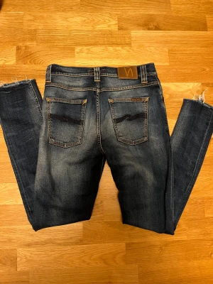 Mörkblå jeans från Nudie - Säljer dessa extremt feta nudie jeans. Dessa jeans är väldigt eftertraktade på marknaden just nu🍾W30 L32. modell Lean dean. Har en lagning i skrevet som jag själv tycker är en fet detalj men bra att veta  Tveka inte att fråga vid minsta fundering!
