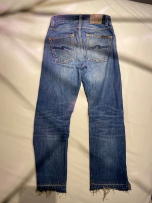 Nudie Jeans Loose Leif blå jeans W26 L30 - Säljer ett par Nudie Jeans Loose Leif i tvätten Classic Crumble. De är blå, har en loose passform och raka ben med rå, fransig kant nedtill. Tillverkade i 100% ekologisk bomull. Klassiska femficksjeans med orange sömmar och Nudie-logga på bakfickan. Skriv om du har frågor!
