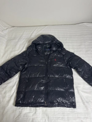 Polo Ralph Lauren Glossy Jacka - Svart Polo Ralph Lauren Glossy Jacka i storlek Medium.   Endast testad och icke använd, jackan är i nyskick och fri från defekter! Säljes då jag köpt ny jacka.  Finns att hämta i Jönköping och kan fraktas. Hör av dig vid frågor eller funderingar! 