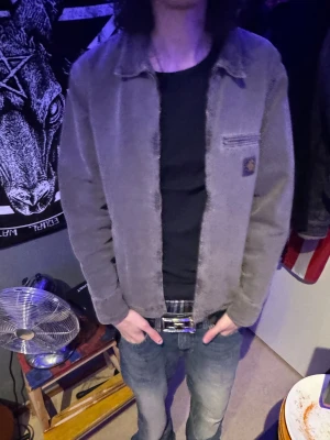 Grå grön Carhartt jacka - Säljer en grå overshirt jacka från Carhartt med klassisk krage och diskret logopatch på bröstet. Jackan har en rak passform, dragkedja framtill och är tillverkad i slitstark bomull. Perfekt för dig som gillar streetwear och vill ha en clean look.