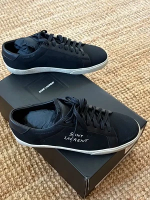 Saint Laurent sneakers i storlek 41 säljes. -   Saint Laurent sneakers i storlek 41 säljes.  • Original Saint Laurent sneakers • Svart, stilren design med vit sula • Modern modell som passar vardag och mer uppklädda outfits • Aldrig använda • Fick skorna i present • Säljs på grund av fel storlek • Originalkartong ingår • Äkthetskort från Saint Laurent medföljer som bevis  Skorna passar dig som vill ha exklusiva sneakers med tydlig och enkel design. Ett bra val för dig