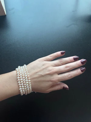 Pärlarmband med ljusrosa pärlor - Snyggt armband med sex rader vita pärlor och silverfärgat spänne (stainless steel)Längden är cirka 20 cm med justerbar kedja.  Helt nytt! Buda gärna! 