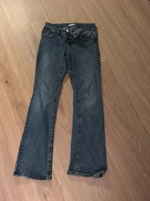 Blå bootcut jeans från Gina - Säljer ett par klassiska blå jeans från Perfect Jeans i bootcut-modell. Jeansen har fem fickor, knapp- och dragkedjestängning samt snygga detaljer på bakfickorna. De är använda men fortfarande i ett bra skick. 
