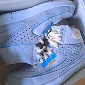 Nike Jordan 2 Air Flight Union(Grey Fog) - Nike Jordan 2 sneakers i ljusblå mocka med perforerade paneler och vita snören. Skorna har blå detaljer och en klassisk rund tå. Kommer i originalkartong med Jordan-logga på insidan av locket. Perfekt för dig som gillar stilrena och sportiga sneakers.