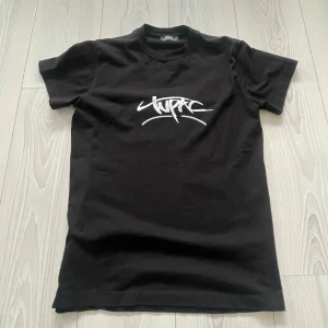 Svart Tupac t-shirt från Dolce & Gabbana - Svart t-shirt från Dolce & Gabbana med Tupac-tryck i vitt framtill och stor färgglad illustration på ryggen. Skön passform och cool streetstil, perfekt för dig som gillar hiphop och unika plagg. Vid intresse skicka! 