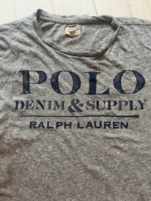 Grå t-shirt Polo Ralph Lauren - Snygg Ralph Lauren topp! Den är nästan aldrig använd men köpt second hand. Den har inga stora defekter eller tecken på använding. Hör av er vid frågor!😊