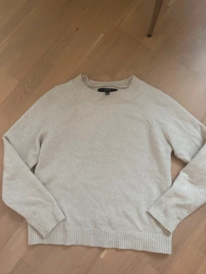 Beige stickad  - Säljer en stilren beige stickad tröj.  Tröjan har rund hals, ribbade muddar och nederkant samt långärmad passform. Perfekt för lager-på-lager och enkel att matcha med jeans eller kjol.