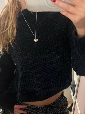 Mörkblå stickad tröja med ribbad kant - Mysig mörkblå stickad tröja med grov struktur och ribbad kant vid hals, ärmslut och nederkant. Tröjan har en loose passform och långa ärmar, perfekt för kyliga dagar. Enkel och stilren design som funkar till många olika outfits.