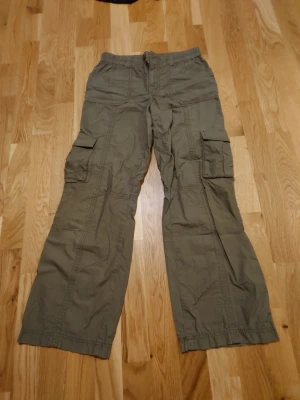 Gröna Cargo byxor  - Snygga cargo byxor från Gina Tricot. Använda men bra skick. Små missfärgningar på fickorna (se bilder) men inget som man ser när de är på. Åt det kortare hållet, passar va 165 och kortare. 