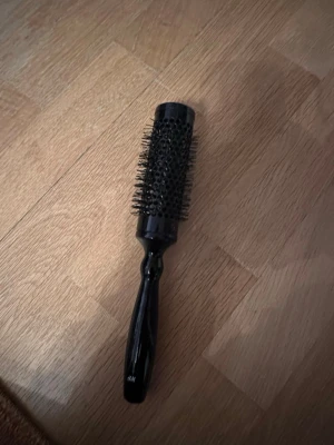 Rund borste från H&M  - Säljer en rund borste från H&M, perfekt för styling och föning. Borsten är helt svart med ett cylinderformat borsthuvud och många täta plastpiggar. Handtaget är ergonomiskt och också svart, tillverkat i plast. Passar dig som vill ha volym och snygga lockar.