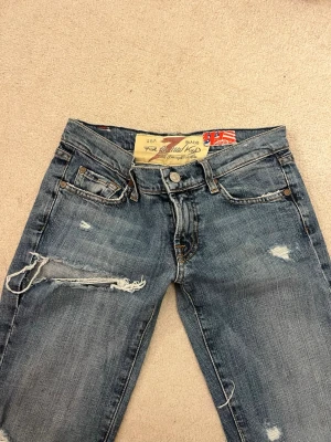 Jeans  - Säljer dessa blåa jeans med hål. De har design på bakfickorna är låga i midjan och bootcut. Säljer pga att de inte passar längre kan därför tyvärr inte skicka bild me de på. Pris kan diskuteras har ni andra frågor är det bara att skriva till mig!❤️     Midjemått:36cm rakt över  innerbenslängd:77cm