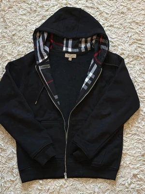 Svart burberry hoodie med röda stripes - Måste in i tvätten. Annars e den väldigt deformerad