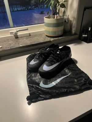 Nike Mercurial elite AG - Säljer ett par svarta Nike Mercurial elite fotbollsskor med ljusblå detaljer. Skorna är gjorda för spel på konstgräs med AG-dobbar (går även att använda på naturgräs).                                                                          Skick 9,5/10 i princip nyskick de är bara testade på konstgräs max 2 gånger. Skriv dm för mer info! 