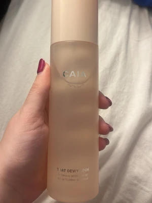 CAIA That Dewy Look Setting Spray - Ljusbeige, frostad flaska med CAIA-logga. Setting sprayen 'That Dewy Look' ger en fräsch och återfuktad finish till din makeup. Innehåller 200 ml och har en stilren, minimalistisk design. Perfekt för dig som vill ha glow och långvarigt resultat.