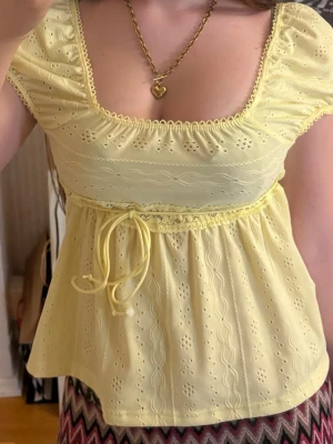 Ljusgul 2000s broderad babydoll topp - Söt ljusgul topp med broderade detaljer och puffärmar. Toppen har fyrkantig ringning, knytband i midjan och spetskant. Tyvärr köpte jag den på plick och lapp va bortklippt så vet ej märke!🤍Passar mig som ofta bär S