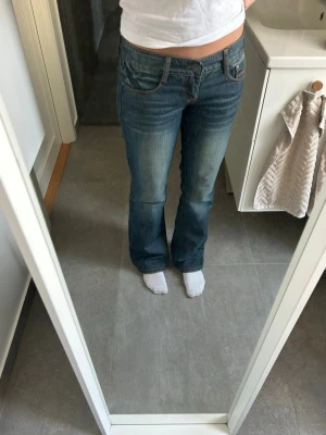 Vintage bootcut jeans  - Snygga blå vintage bootcut jeans med låg midja. Jeansen har fint mönster på fickorna. Jättebra skick, storlek 28, passar storlek S i jeans! 