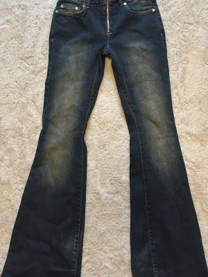 Bootcut jeans från Weekday, mörkblå - Säljer ett par mörkblå bootcut jeans från Weekday med snygga slitningar framtill. Jeansen har klassisk femficksdesign, dragkedjegylf och är tillverkade i denim. Perfekta för dig som gillar en retroinspirerad look med utsvängda ben.