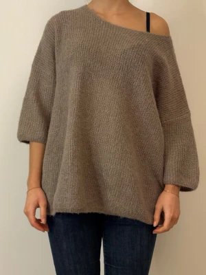 Beige oversized stickad tröja - Säljer en beige oversized stickad tröja med bred halsringning som kan bäras off-shoulder. Tröjan har trekvartsärmar och är gjord i ett mjukt, grovt stickat material. Perfekt för lager på lager och en avslappnad look.