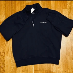 Abercrombie & Fitch Sweatshirt  - Mörkblå – Storlek M | Abercrombie & Fitch Premium Polished Logo Half-Zip Sweatshirt  Helt ny och oanvänd med prislapp kvar. Broderad logga, half zip med mockneck-krage och mjukt fleecefoder. Perfekt för chill dagar.