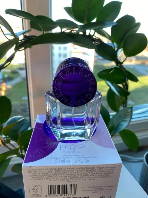 Stella McCartney POP Bluebell parfym - POP Bluebell från Stella McCartney är en Eau de Parfum i en unik, transparent glasflaska med lila detaljer och ett runt, lila lock med logotypen ingraverad. Flaskan rymmer 30 ml och har en modern, stilren design som sticker ut på parfymhyllan.
