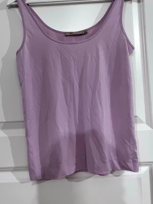 Ljuslila linne från Whyred - Säljer ett stilrent ljuslila linne från Whyred i mjukt material. Linnet har rundad halsringning och smala axelband, perfekt för att skapa en clean och enkel look. Passar xs till en liten medium