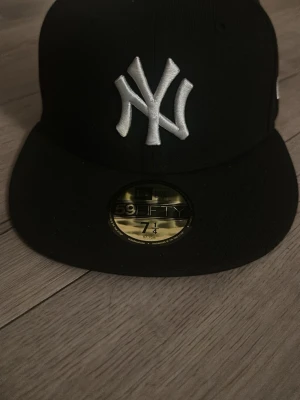 Svart New Era Yankees keps 59FIFTY - Snygg svart keps från New Era med klassiskt New York Yankees-broderi framtill i vitt. Modellen är 59FIFTY med rak skärm och broderad logga på sidan. Perfekt för dig som gillar streetwear och sportig stil. Den är använd 2 gånger så helt ny skulle jag säga 