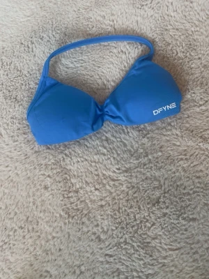 Blå gymset från DFYNE - Snyggt blå gymset från DFYNE med enkel axelrem och vit logga på ena sidan. Tillverkad i stretchigt material som sitter bekvämt och passar perfekt till gymmet. Säljer både toppen och byxorna tillsammans.