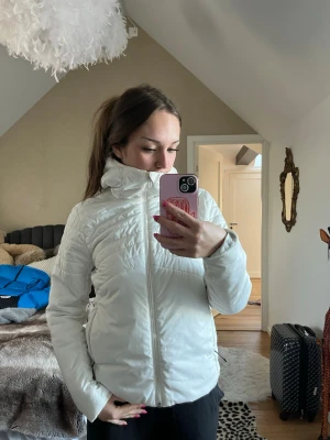 Vit dunjacka med hög krage - Säljer en vit dunjacka med dragkedja framtill och hög krage. Jackan har en stilren design och är perfekt för vardag eller skidor. Passar dig som vill ha en varm och lätt jacka med modern look. Storlek M men passar bra på mig som är s