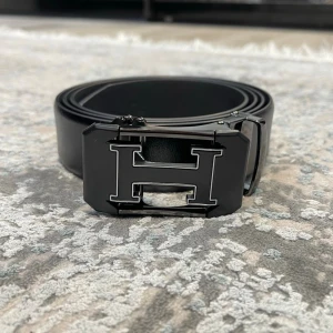 Läderbälte med automatiskt spänne – justerbar längd  - 📏 Storlekar: 130 cm & 135 cm Kan enkelt klippas i änden för perfekt passform.  🧵 Design: • Texturerat läder för en klassisk look • Slät läderfinish för en stilren, minimalistisk känsla (Bilder kan skickas vid intresse)  🔒 Automatiskt spänne: Smidigt klicksystem på insidan som sitter stadigt och enkelt justeras. Ger ett elegant och minimalistiskt uttryck.  🎨 Välj din logga: Flera loggor finns – välj din favorit. kolla min profil för alla alternativ 😊  📦 Snabb leverans 💬 Frågor? Hör av dig!