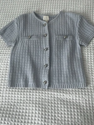 Ljusblå stickad kortärmad kofta -  ljusblå stickad tröja med knappar. Använd endast 1 gång. Stl S