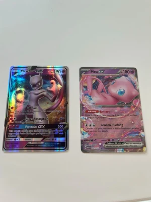 Pokémonkort Mewtwo GX & Mew GX - Två Pokémonkort: Mewtwo GX med holografisk yta och Mew GX med färgglad design. Båda korten är på engelska och har unika attacker och HP. Perfekt för samlare eller Pokémonfans som vill utöka sin kortsamling.