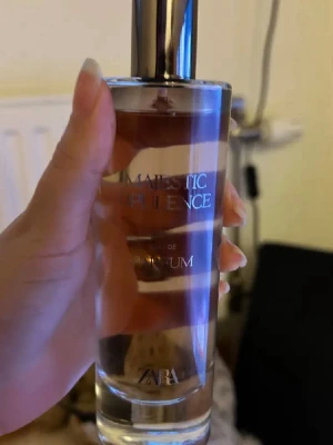 ZARA Majestic Opulence Parfym - ZARA Majestic Opulence är en elegant parfym i en genomskinlig glasflaska med silvrig spraykork. Flaskan har en stilren och modern design med text i vitt. Perfekt för dig som gillar exklusiva dofter och snygga flaskor att ha framme.