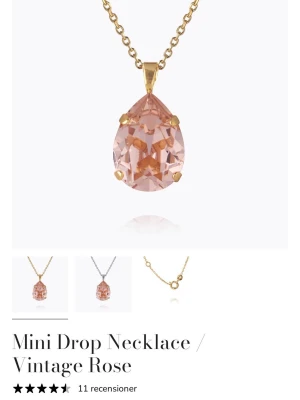 Mini Drop Necklace Vintage Rose Caroline svedbom  - Guldpläterat halsband med en droppformad, rosafärgad kristall som hänge. Kedjan är tunn och elegant, och hänget har en vintagekänsla med sin mjuka rosa ton och gnistrande yta. Perfekt för dig som gillar stilrena och romantiska smycken. Helt ny, oanvänd!!