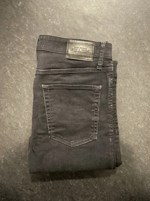 Jack & Jones jeans (slim fit Tim) - Säljer ett par svarta Jack&Jones jeans, storlek 32/32, slim fit. Mycket bekväma jeanst och är lite stretchiga. Mycket fint skick där de har använts fåtal gånger.                                    Nypris 700kr                                                   Mått: A=42cm B=77cm C=103cm D=17cm      Fråga gärna om fler bilder eller om det är något ni generellt undrar!                                                     Checka in profilen för liknande jeans!