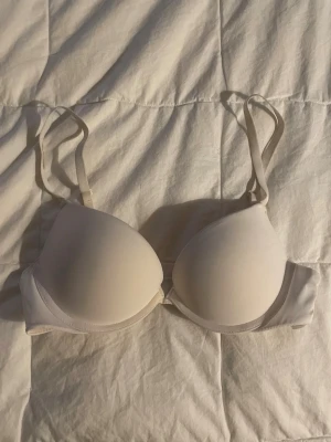 Beige push-up bh från H&M - Säljer en enkel och stilren beige push-up bh från H&M med justerbara axelband och bygel. Bh:n har släta kupor och är tillverkad i polyester och elastan för en bekväm passform. Perfekt under ljusa toppar och tröjor.
