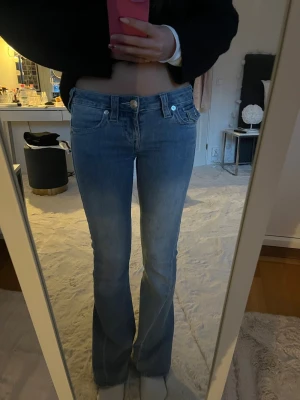 Blåa lågmidjade bootcut jeans från True Religion  - Säljer ett par ljusblåa lågmidjade jeans från True Religion med en bootcut passform i storlek 24. Jeansen är sparsamt använda och har inga defekter, nypris är 1300kr💕💕