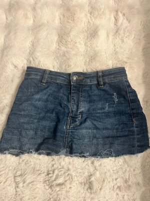 Blå jeanskjol från hm, strl 34 - Säljer en blå jeanskjol från HM i storlek 34. Kjolen har klassisk femficksdesign, knapp och dragkedja framtill samt rå kant nedtill för en cool look. Perfekt för dig som gillar denim och vill ha en kortkjol med avslappnad stil.