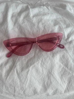 Rosa cat eye solglasögon från CHIMI - Säljer ett par snygga rosa cat eye solglasögon från CHIMI. Glasögonen har genomskinlig båge och matchande rosa glas, vilket ger en riktigt trendig och lekfull vibe. Perfekta för dig som vill sticka ut och addera färg till din look.