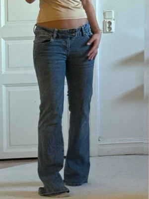 Blå bootcut jeans med låg midja - Snygga blå bootcut jeans med låg midja och klassisk femficksdesign. Jeansen har en avslappnad passform och är perfekta för en trendig vardagslook. Tillverkade i mjuk bomull för skön känsla hela dagen.