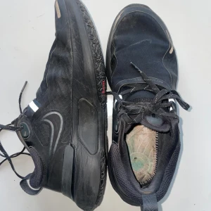 Nike React svarta sneakers strl 40 - Svarta Nike React sneakers med snygga reflekterande detaljer och klassisk swoosh på sidan. Skorna har snörning, platt sula och är tillverkade i syntetmaterial och mesh för bra andningsförmåga. Saknar sula. 