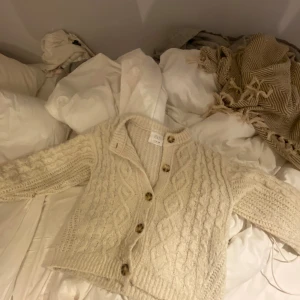Beige stickad kofta från ZARA - Supermysig beige stickad kofta från ZARA med kabel stickat mönster och stora knappar! Jätte söt, är i storlek 152 men passar xs!💞