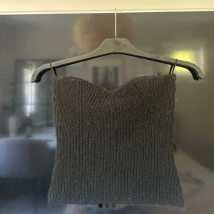 Stickad svart tubtopp från Gina Tricot - Mysig stickad tubtopp från Gina Tricot i svart. Toppen är ribbstickad och har en bandeauformad passning som sitter snyggt över bysten. Perfekt att styla med jeans eller kjol för en trendig look.