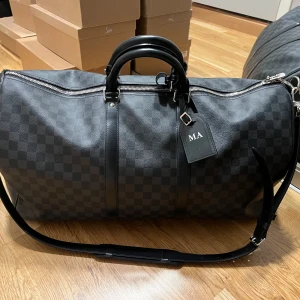 Louis Vuitton Keepall 55 Damier Graphite - Knappt använt min bag, den är som ny, har kanske 1-4 märken på den men de är knappast synliga. Kommer med allt, nycklarna, nyckellåset, dustpåsen till nycklarna, dustpåsen till väskan, boxen, brevet med kvitteringen. Köpt från LV butiken i Oslo.