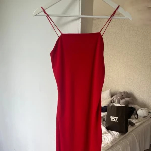 Röd kort klänning från BikBok XS - Snygg röd klänning från BikBok i storlek XS med tunna axelband och rak halsringning. Klänningen är kort och har en enkel, stilren design som sitter figurnära. Perfekt för dig som vill sticka ut med en färgstark look.